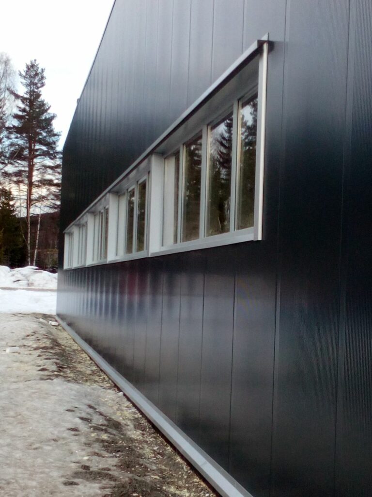 Boczna elewacja hali z płyt warstwowych w kolorze grafitowym RAL 7016 – hala stalowa w Norwegii